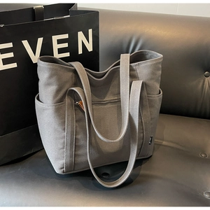 Detail view of grey canvas tote bag with multi-pocket structure and durable shoulder straps