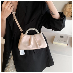 Detail of a beige cloud bag with elegant pearl beads handle and fine pleats