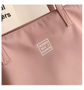 Detail of pink waterproof nylon tote bag featuring reinforced stitching and logo print