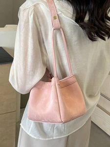 Sac seau en daim rose avec boucle dorée porté par un mannequin pour femme