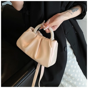 Detailed view of cream pleated cloud bag featuring premium pearl woven ring handle and strap