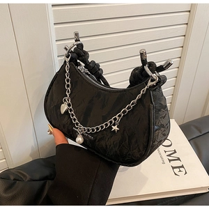 Detail of black pleated crossbody bag with silver heart charms and knotted handle