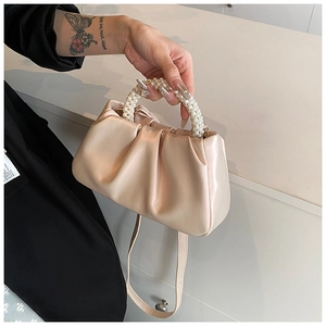 Detail of champagne pleated cloud bag featuring elegant triple-strand pearl handles