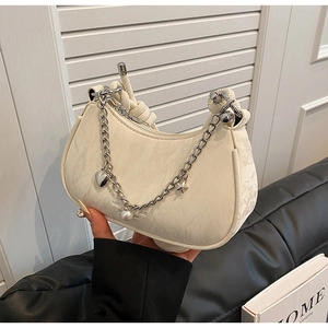 Detail of cream hobo bag with textured fabric, silver chain, and heart charms