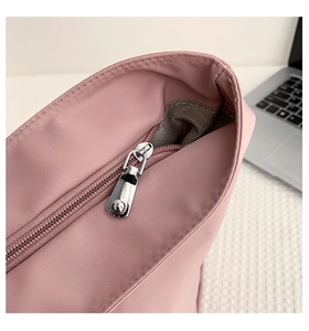Close-up of smooth metal zipper and grey herringbone lining on a pink nylon tote bag