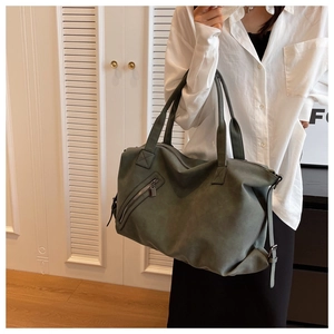Detail of dark green tote bag featuring matte leather texture and metallic zipper pocket