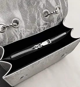 Dettaglio borsa in pelle argentata con cerniera metallica e chiusura a scatto magnetico
