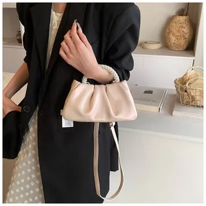 Detail of light beige pleated cloud bag with pearl handle and long leather strap