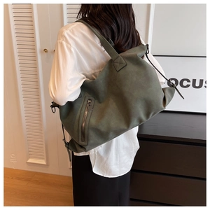Detailed side view of a large olive green matte leather tote bag with a functional zipper pocket