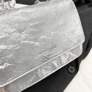 Primo piano della borsa a tracolla argento con texture increspata e dettaglio a sfera