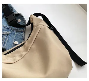 Close-up of beige crossbody bag texture with black strap and denim jacket pairing