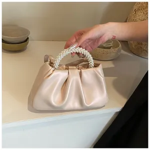 Detailed view of cream cloud bag featuring pleated faux leather and pearl woven handle