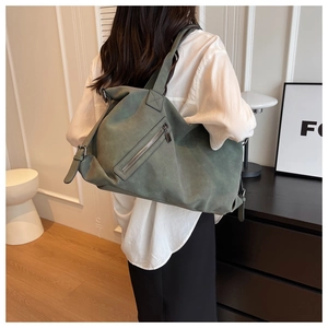 Detail showing high-capacity green tote bag with side zipper and wide shoulder strap