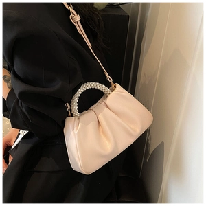 Detailed view of the creamy cloud bag featuring pleated faux leather and pearl handle