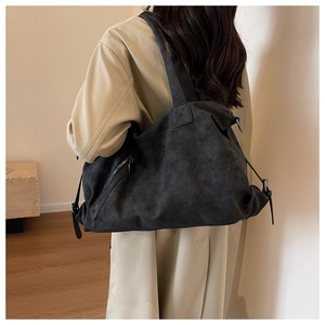 Detail of grey suede tote bag with side zipper and long decorative puller on model