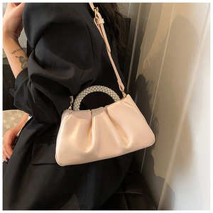 Detail of white pleated cloud bag with pearl handle and shoulder strap on model