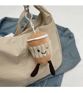 Detail of coffee cup plush charm with cute legs hanging on a stylish beige handbag