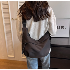 Detail of black crescent crossbody bag showing durable nylon texture and drawstring accents
