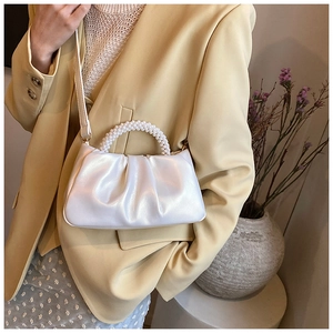 Detail of white pleated cloud bag with pearl handle and glossy pearl finish on shoulder strap