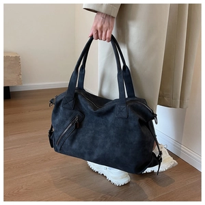 Detail shot of black matte tote bag featuring exterior diagonal zipper and carry handles