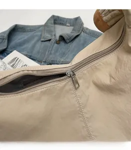 Detailed close-up of smooth silver zipper and durable beige nylon fabric on the commuter bag