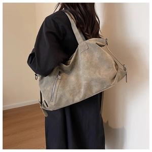 Detailed close-up of a large khaki tote bag showing textured faux leather and metal zippers