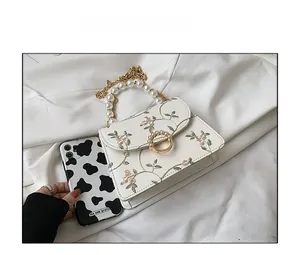 Detail view of lace embroidery and pearl handle on this small white crossbody bag