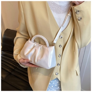 Close-up of pearl handle and pleated texture on creamy cloud shoulder bag for women