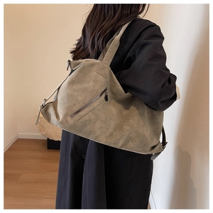 Detail of olive green suede tote bag showing front metal zipper and matte texture