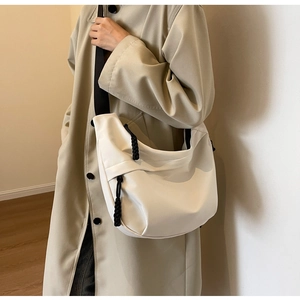 Detailed view of white nylon crescent bag with adjustable black strap on a model