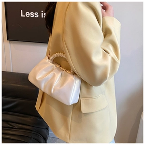Detail of elegant pearl handle and pleated pearlescent cloud bag with gold hardware