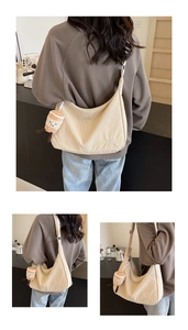 Close-up of beige Oxford fabric hobo bag featuring wide strap and cute plush charm detail