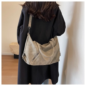 Detail of grey suede tote bag showing large capacity and detachable strap on black coat