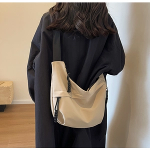 Model view of beige Oxford crossbody bag with black drawstring details and nylon strap