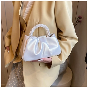Detail of the pearlescent pleated cloud bag with elegant pearl woven top handle