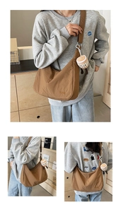 Close-up of brown canvas crescent bag featuring Hoog embroidery and plush coffee cup charm