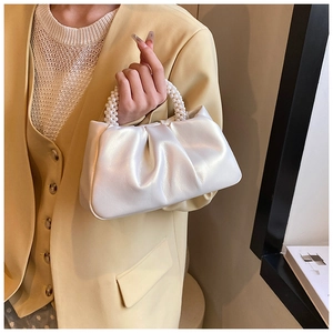Detail of white pleated cloud bag with elegant pearl beaded handle and pearlescent finish