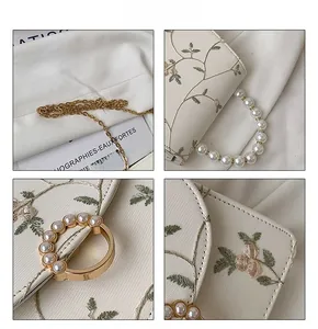 Close-up of floral embroidery on lace crossbody bag with pearl buckle and gold chain