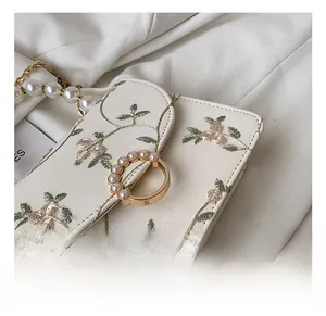 Detailed macro of the gold circular lock with inlaid pearls on the lace embroidery bag
