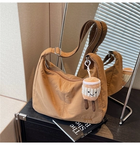 Detail of khaki nylon hobo bag with adjustable strap and plush coffee cup charm