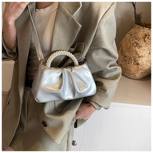 Detailed view of silver pleated cloud bag featuring premium pearl handle and metallic finish