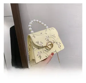 Detail of lizard-patterned leather bag with floral embroidery and pearl handle