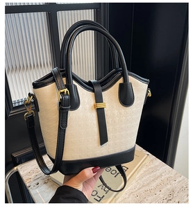 Detail of elegant two-tone cream bucket bag with textured houndstooth finish and gold hardware