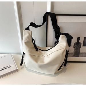 Detail of minimalist beige nylon dumpling bag with black adjustable strap and buckle