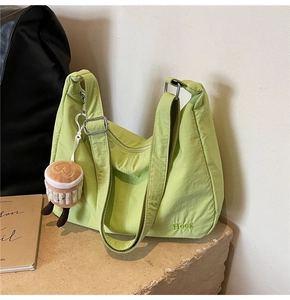 Detail of green half-moon nylon bag with Hoog embroidery and plush cake charm