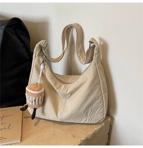 Detail of beige hobo bag with adjustable strap and cute coffee cup plush charm