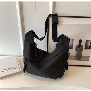 Detail of minimalist black nylon crescent bag featuring wide strap and buckle closure