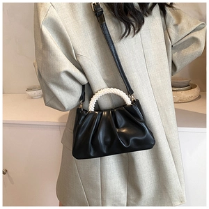 Chic black pleated cloud bag with white pearl handle worn by model in grey blazer