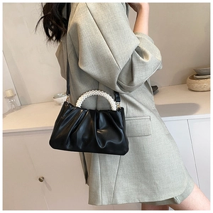 Detail of black pleated cloud bag with elegant pearl handle and slender leather strap