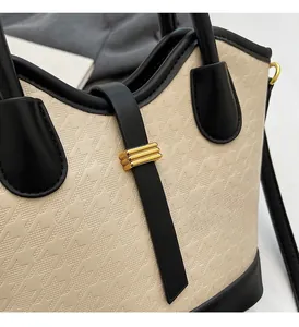 Detail of color-block bucket bag showing cream textured fabric and black leather straps